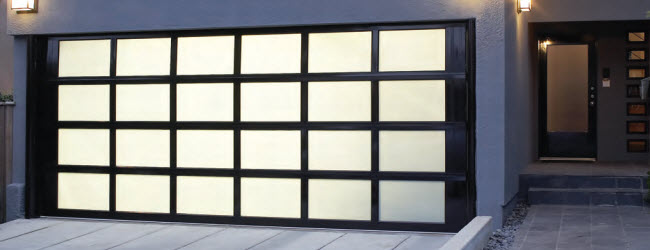 Garage door consisting of a black grid and translucent windows. The door is set in a modern-style home.