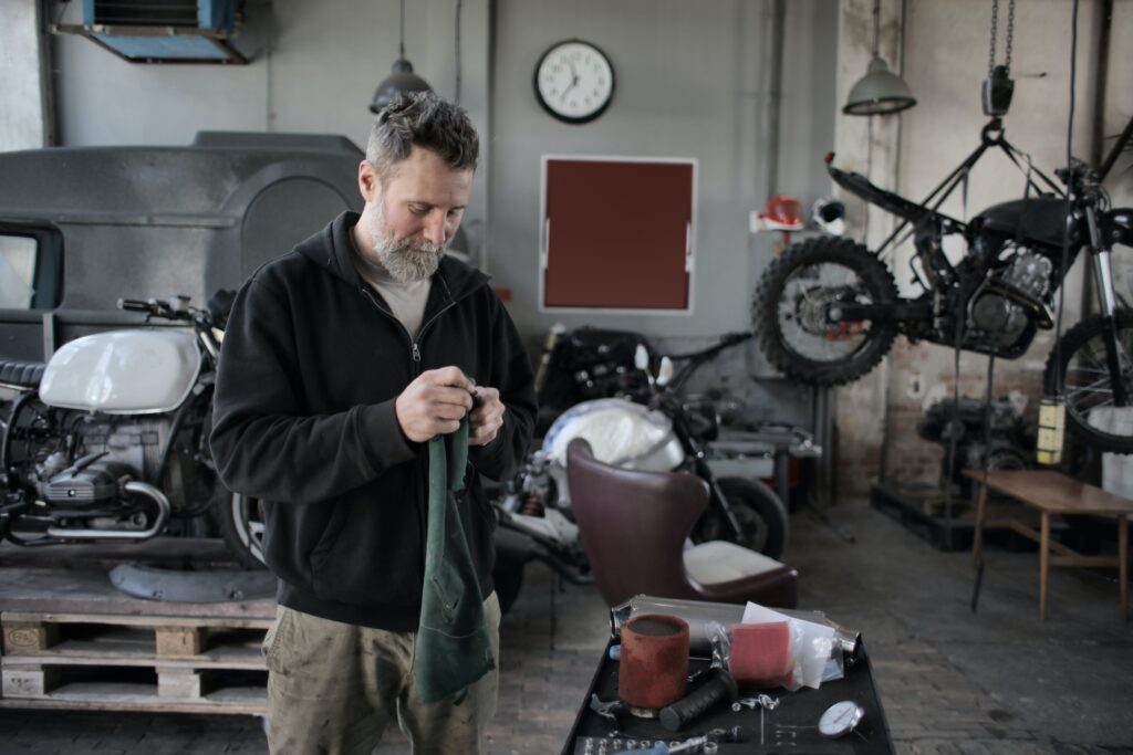 Man standing in garage holding rag.